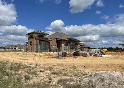 Custom brick home under construction in the Oakmont neighborhood of Bryan, with framed walls and roof structure in progress.