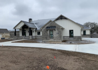 Custom luxury home under construction, two-story residence with stone and stucco exterior and a complex rooflines.